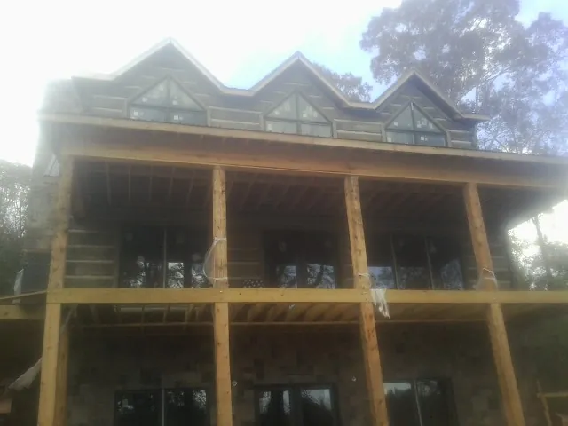 Dormers and porch framing on a large log home under construction — Roof Coating work by our crew in Fort Collins