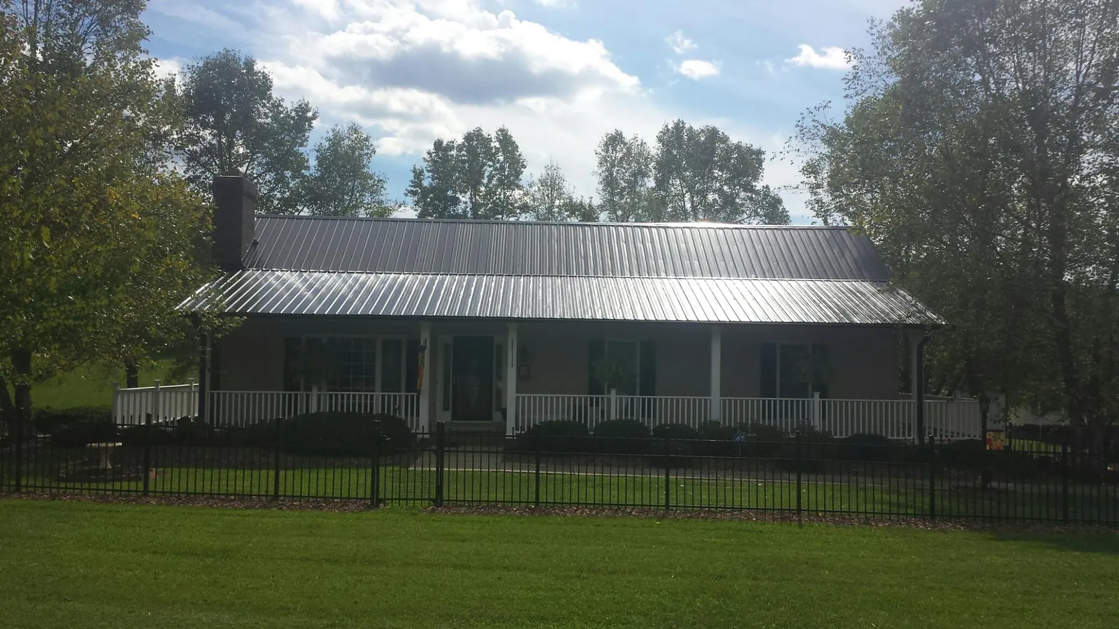 Gray metal roof on a brick ranch with a full width front porch — Gutter Guard Installation work by our crew in Fort Collins