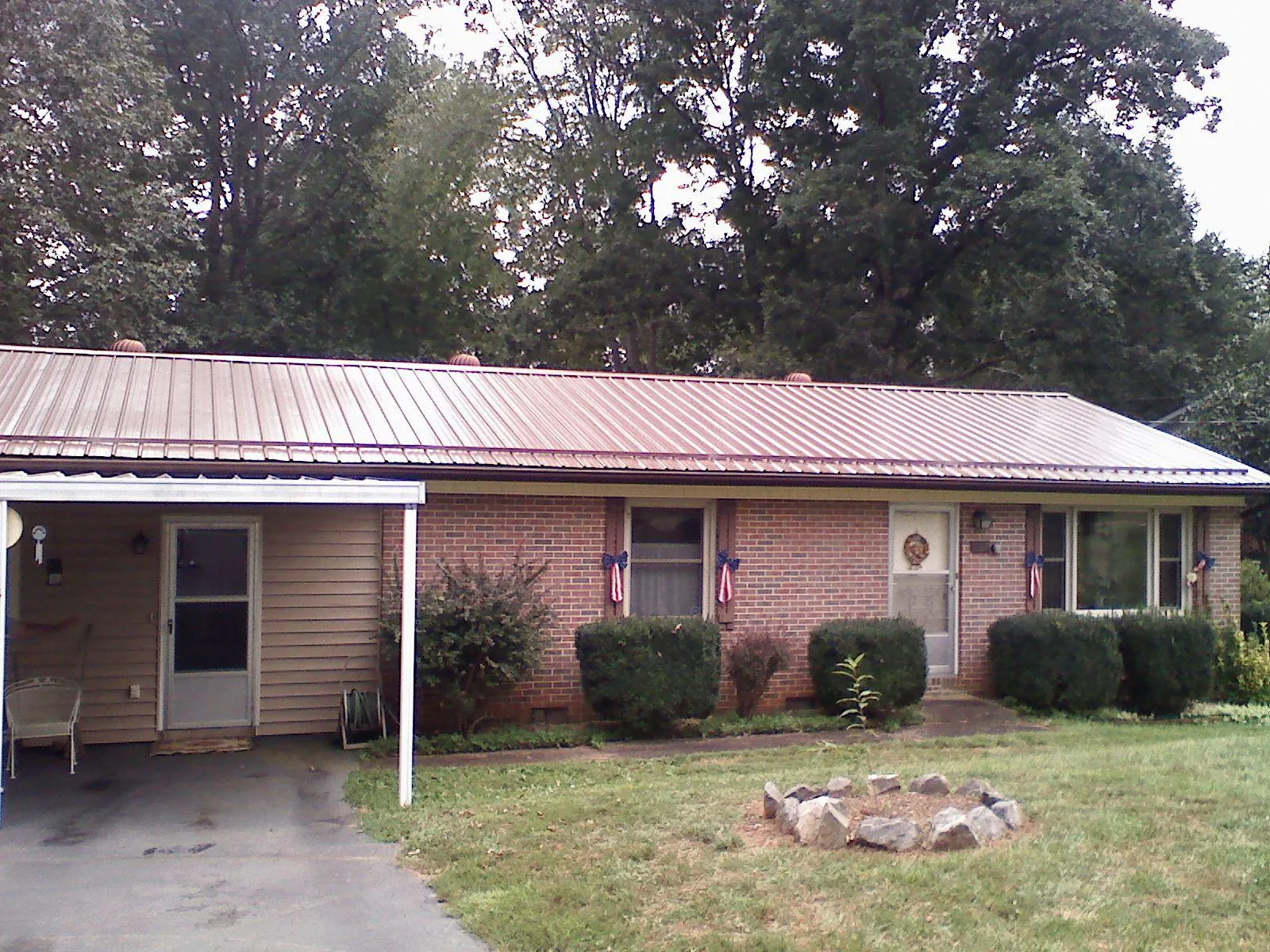 Bronze metal roof and carport on a brick ranch home — Roof Repair work by our crew in Fort Collins