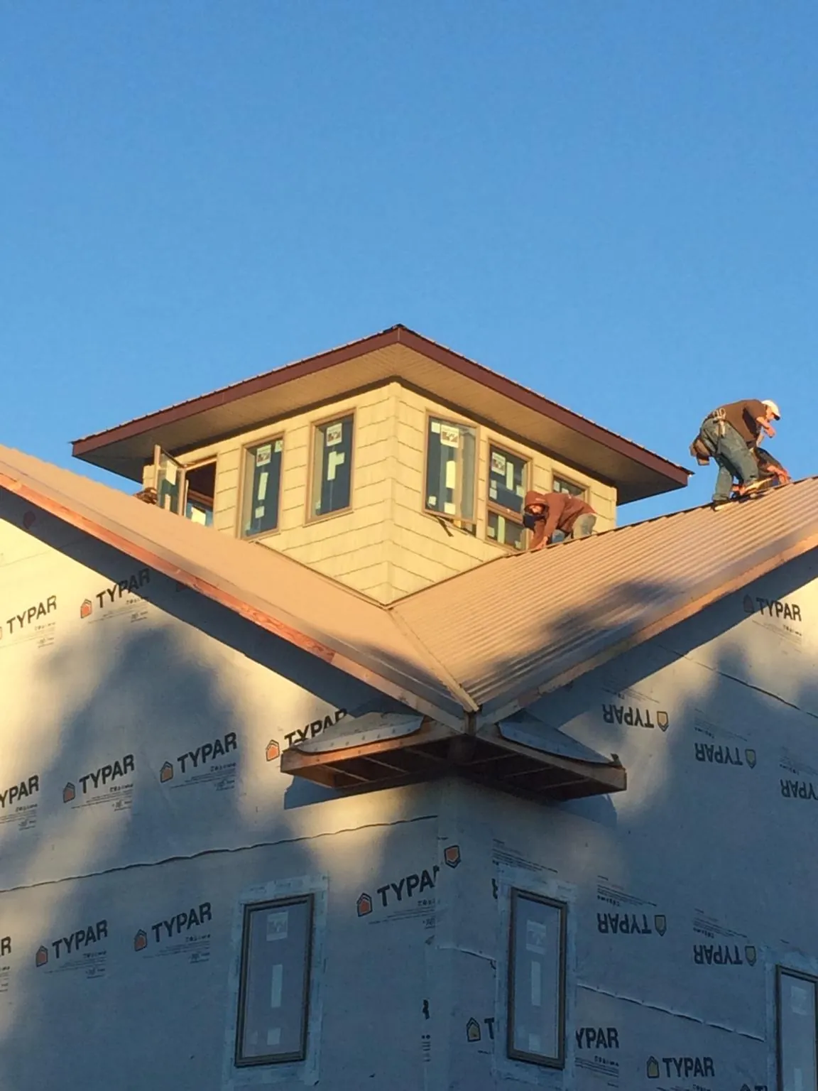 Roofers working around a rooftop cupola on a new metal roof at sunset — Roof Waterproofing in Fort Collins by Roofing Brothers